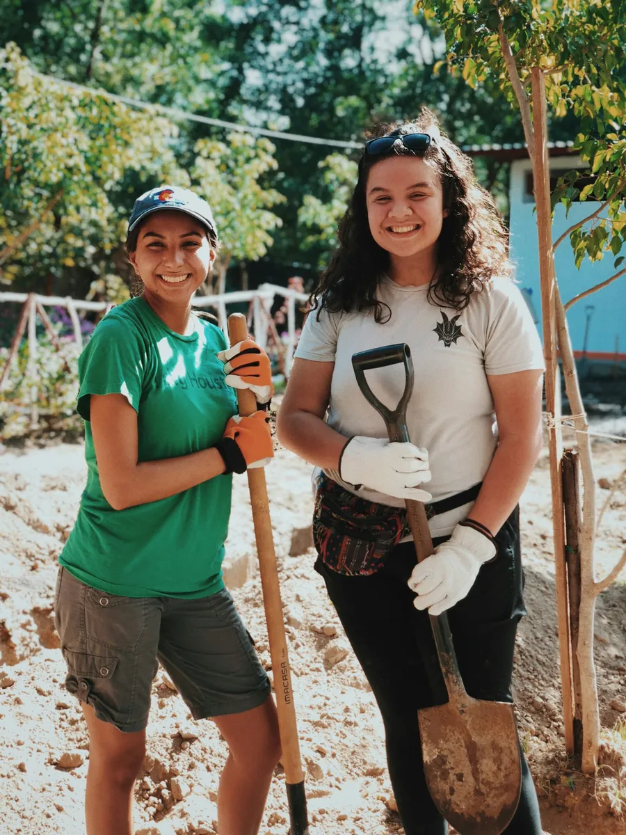 Two volunteers laughing, holding shovels at a tree-planting morning